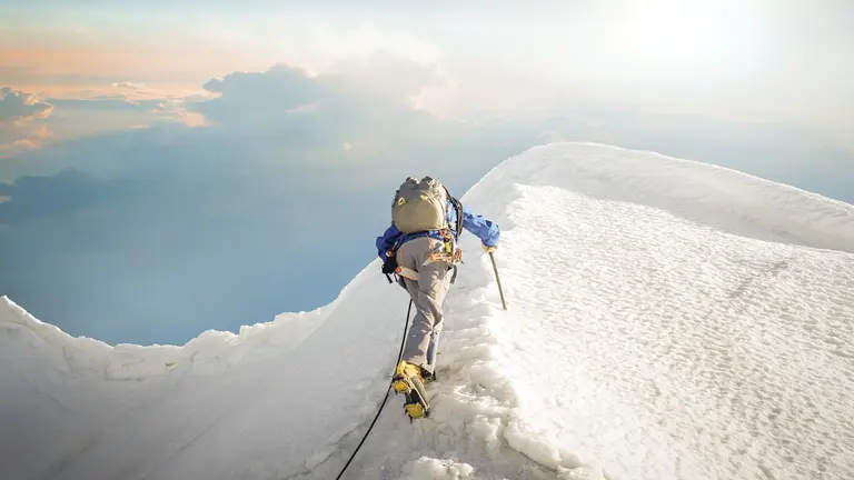 A lone climber ascending a snowy ridge in the Alps